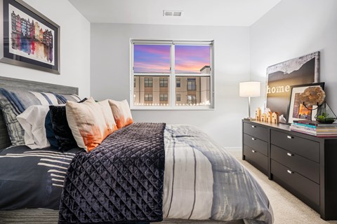 A bedroom with a large bed and a window showing a cityscape.