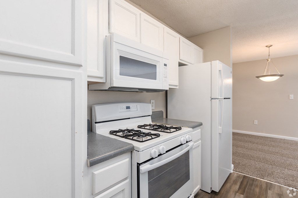 a kitchen with white cabinets and appliances and a white refrigerator
