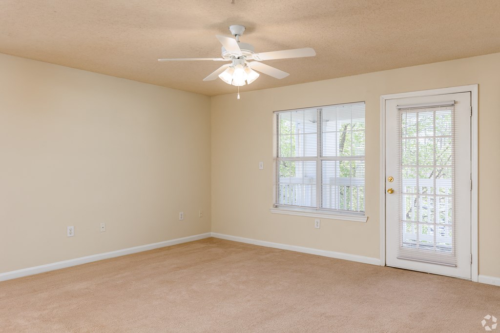 an empty living room with a ceiling fan and a window