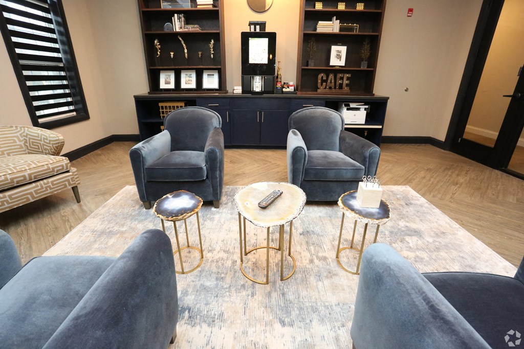 a living room with blue chairs and a coffee table at Century Baxter Avenue, Louisville, KY