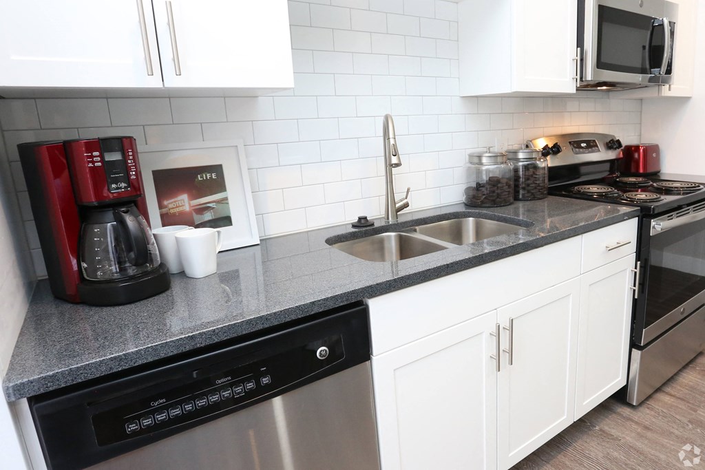 a kitchen with white cabinets and a counter with a sink at Century Baxter Avenue, Louisville Kentucky
