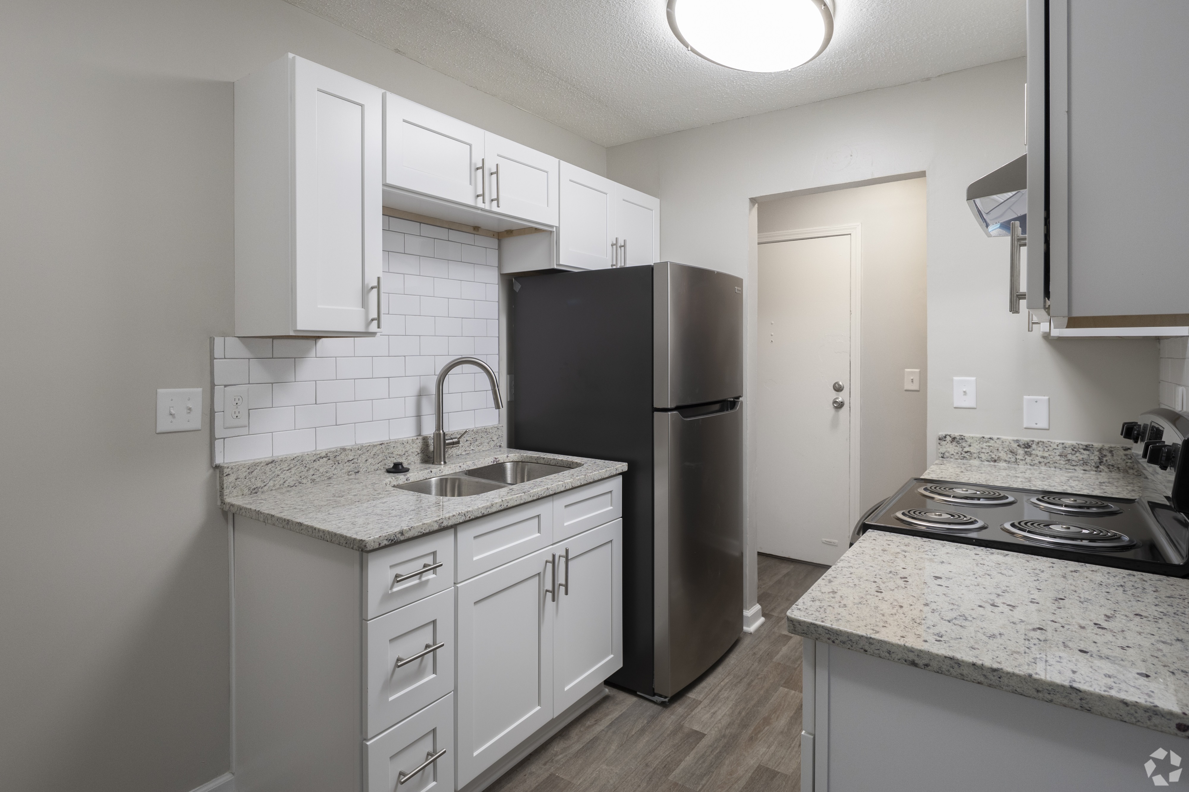 A kitchen with white cabinets and a black refrigerator.