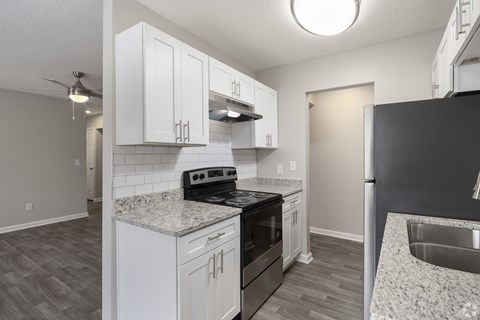 A kitchen with white cabinets and a black stove top oven.
