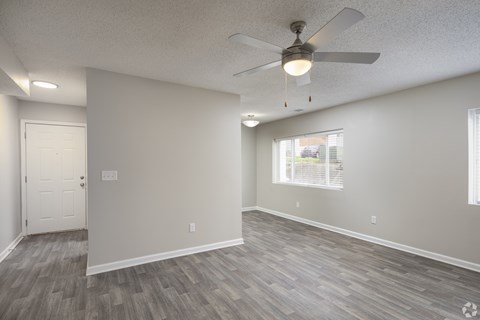 A room with a ceiling fan and a window with blinds.