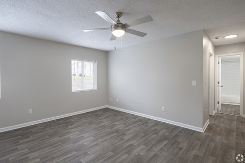 A room with a ceiling fan and wooden flooring.