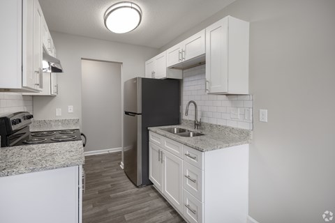 A kitchen with white cabinets and a black refrigerator.