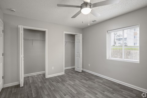 A room with a ceiling fan and a window with blinds.