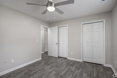 A room with a ceiling fan and three doors.