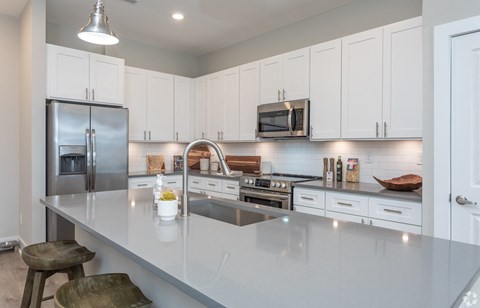 a large white kitchen with stainless steel appliances and a counter top
