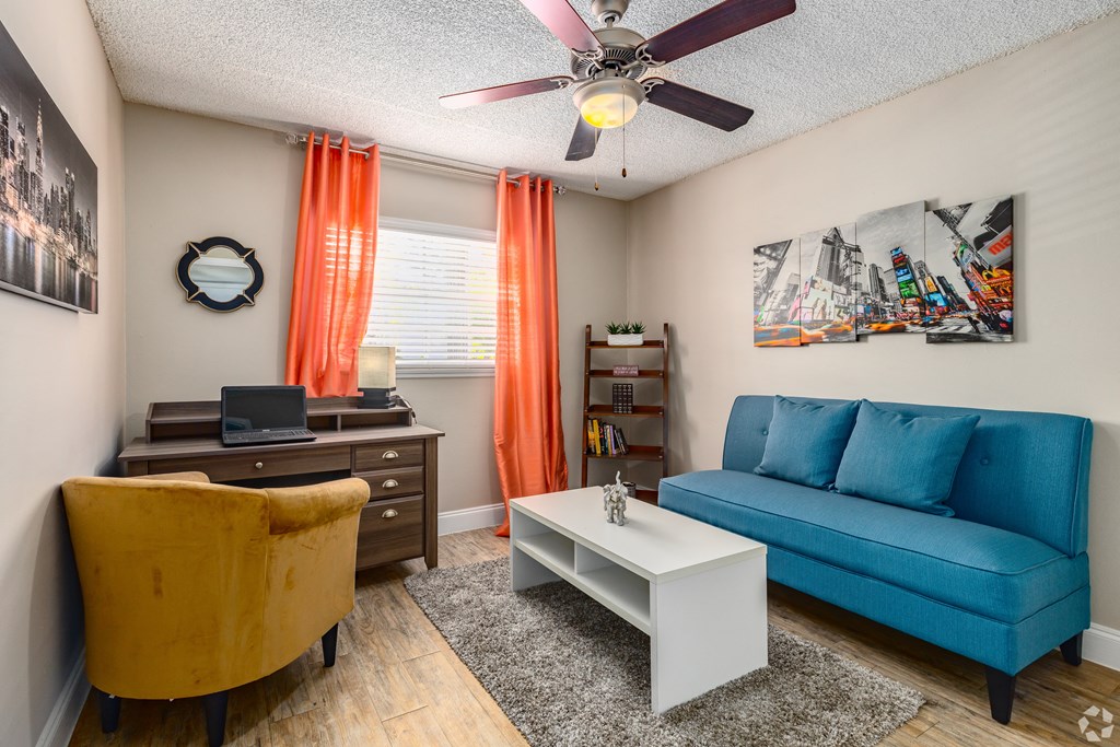 a living room with a blue couch and a white coffee table and a ceiling fan at The Essex, Florida, 32701