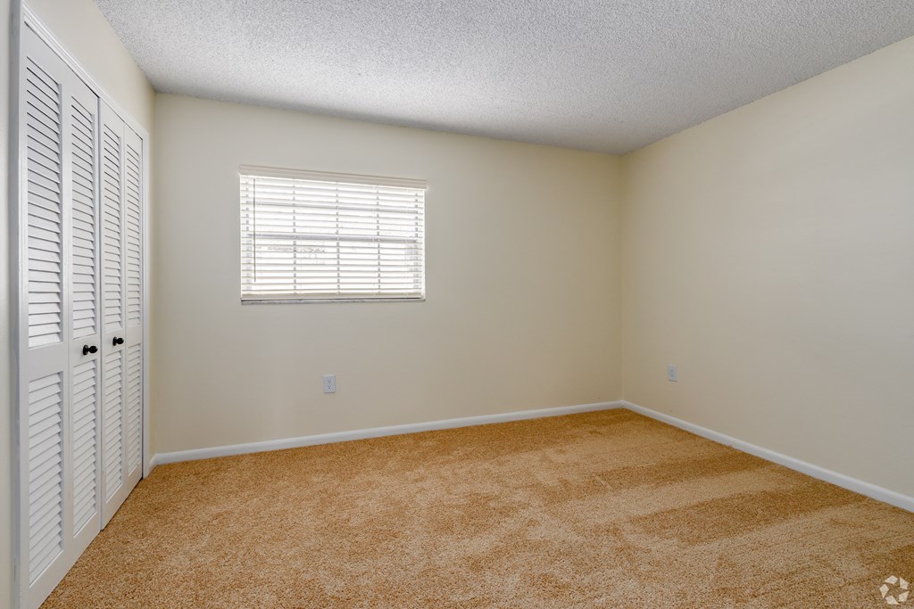 an empty room with a window and a closet