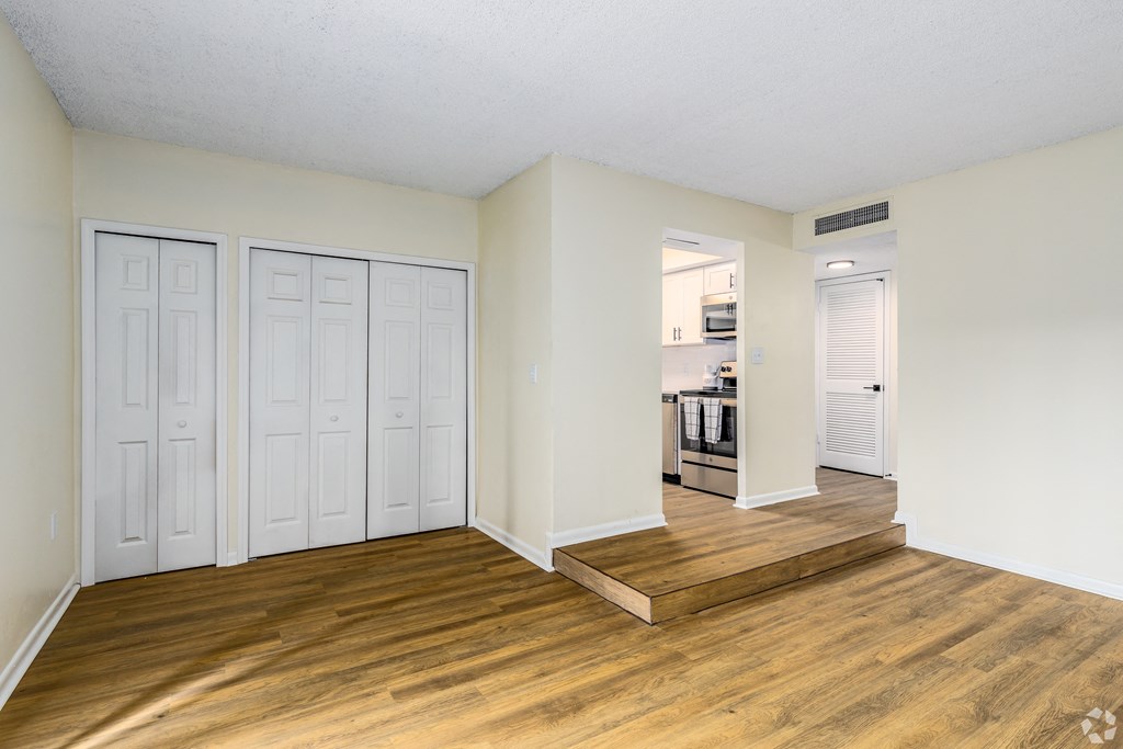the living room and dining room of an apartment with wooden floors and white closets  at The Essex, Altamonte Springs, FL