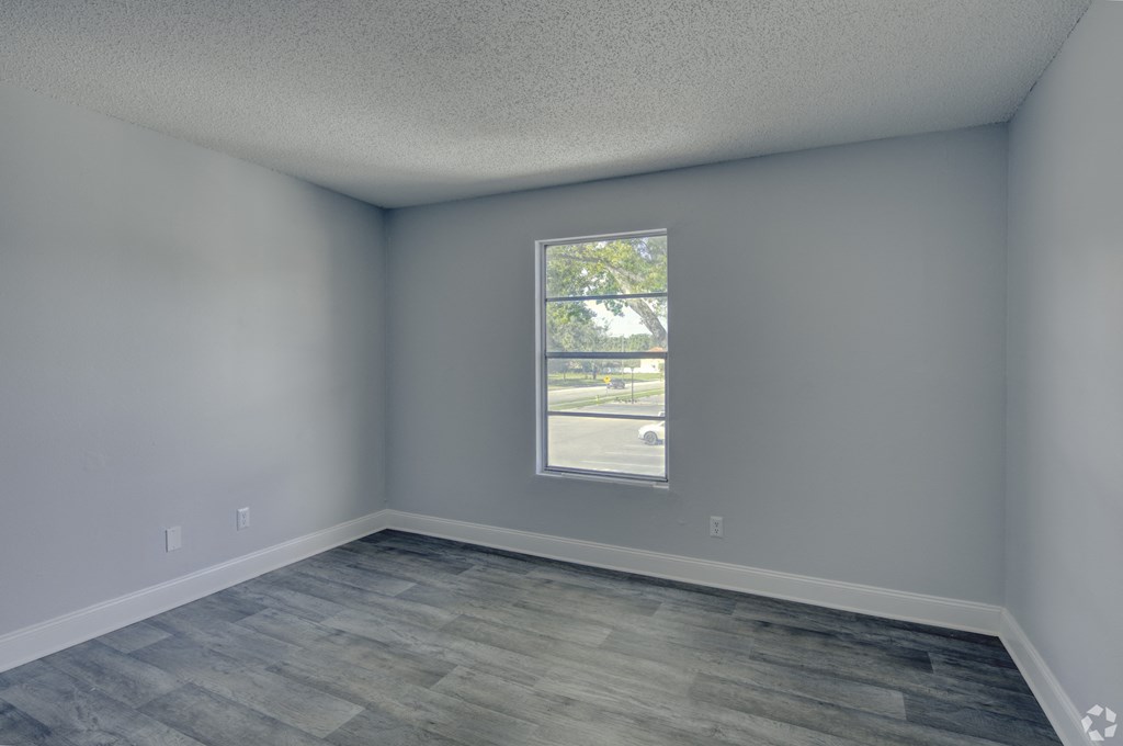 an empty room with gray walls and a window at Beach Club, Tampa