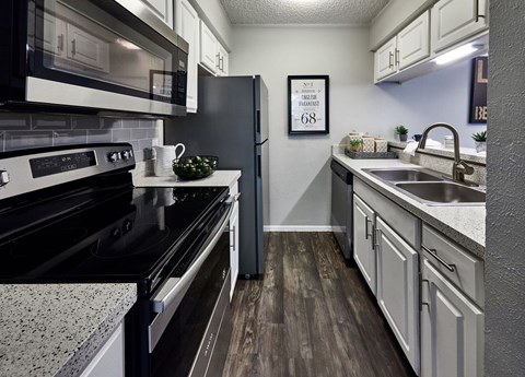 A kitchen with a black stove top oven and a black microwave above it.