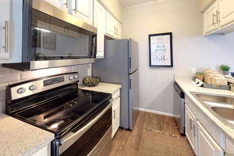 A kitchen with a stove, oven, refrigerator, and a framed picture on the wall.