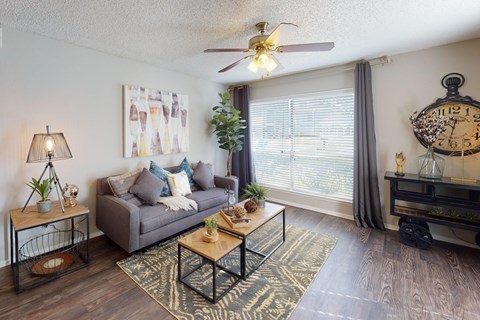 A living room with a grey couch, a coffee table, and a ceiling fan.