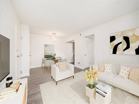A living room with a white couch, a coffee table, and a painting on the wall.