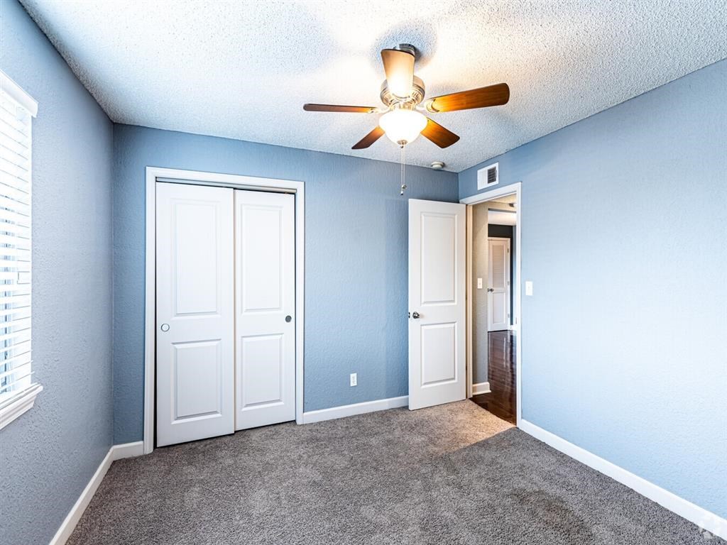 A room with a ceiling fan and two doors.