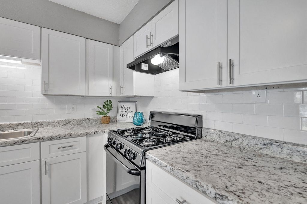 a kitchen with white cabinets and granite counter tops