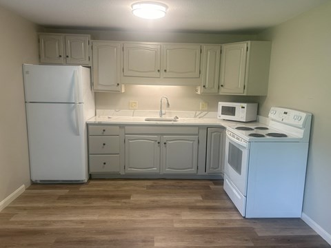 A kitchen with white appliances and wooden floors at Briarcliff at Quechee Apartments, Quechee, Vermont