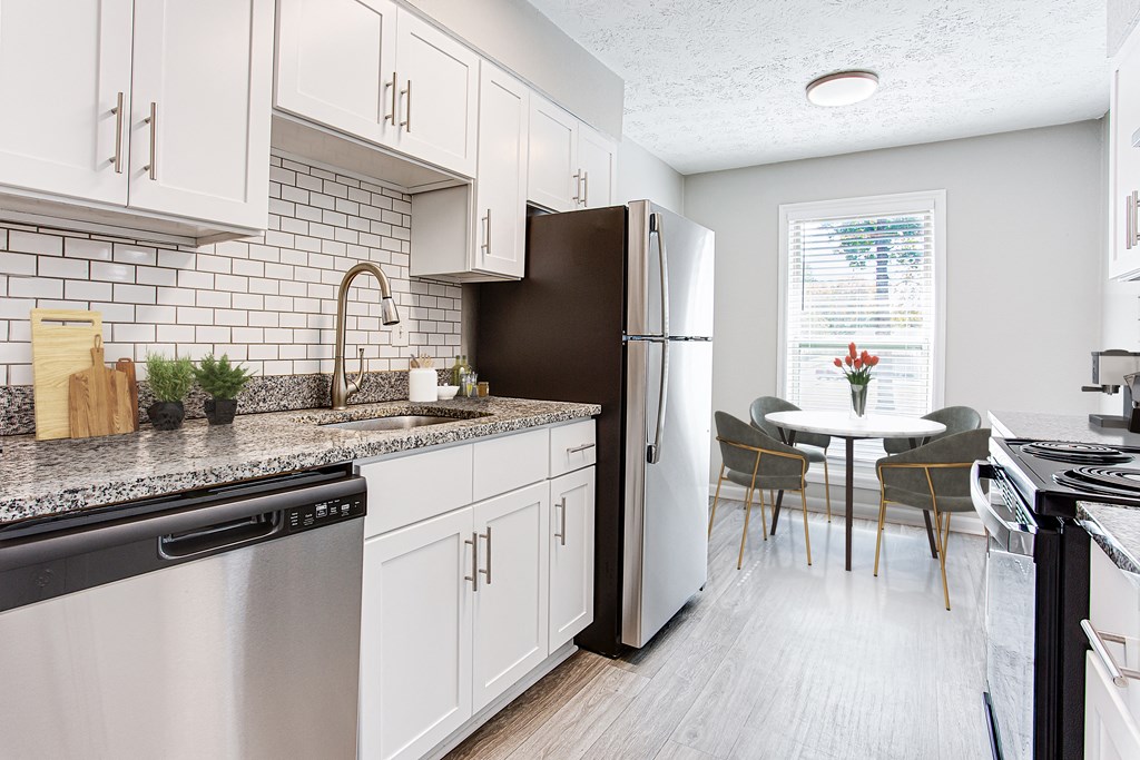 a kitchen with white cabinets and stainless steel appliances and a table and chairs at The Ellis Apartments, Georgia, 30021