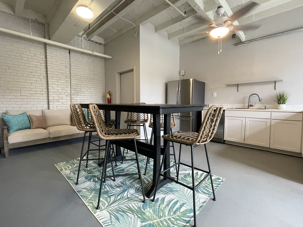 a dining area with a table and chairs and a kitchen in the background