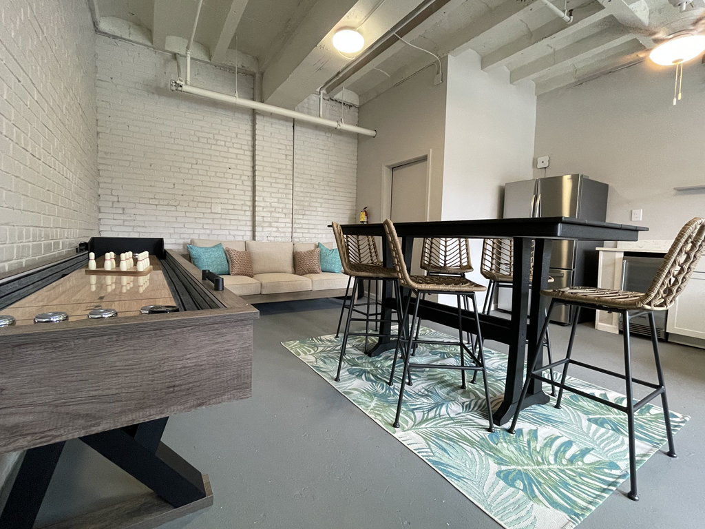 a game room with a pub table and a shuffleboard