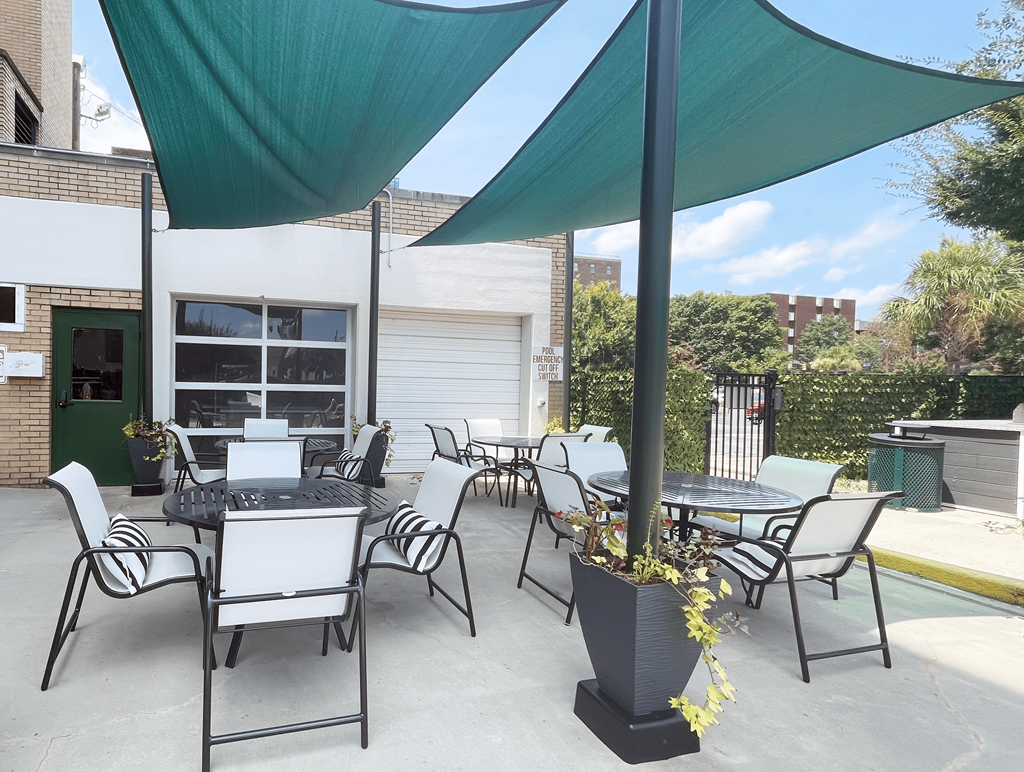 a patio with chairs and tables and a grill