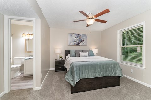 A bedroom with a bed, nightstands, and a ceiling fan.