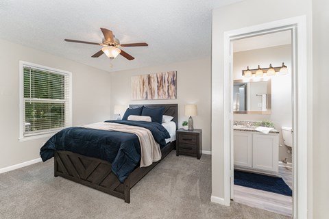 A bedroom with a bed, nightstand, and a ceiling fan.