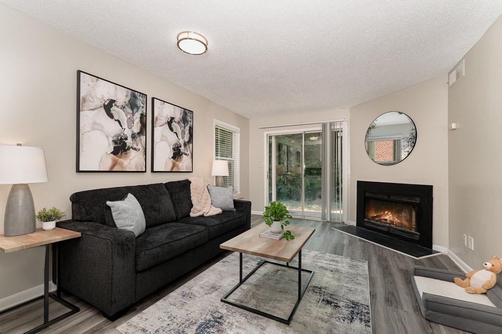 A modern living room with a black couch, a fireplace, and a painting on the wall.