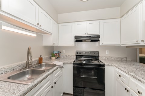 A kitchen with a black stove top oven and a stainless steel sink.