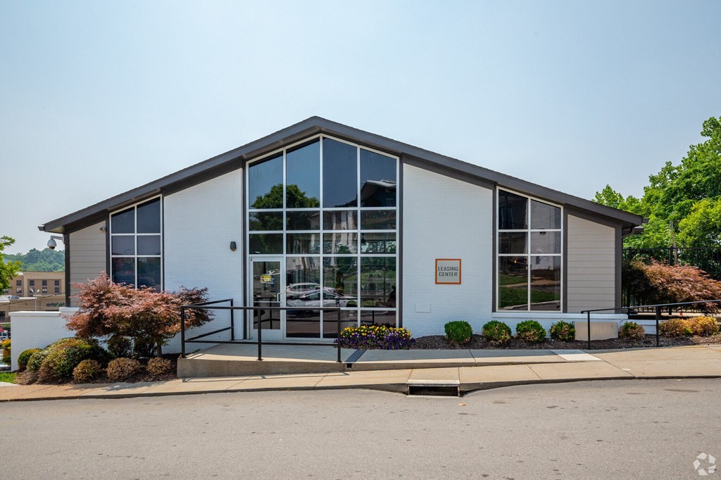 a white building with large glass windows and a black railing in front of it