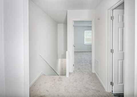 an empty room in a house with white walls and a carpeted staircase