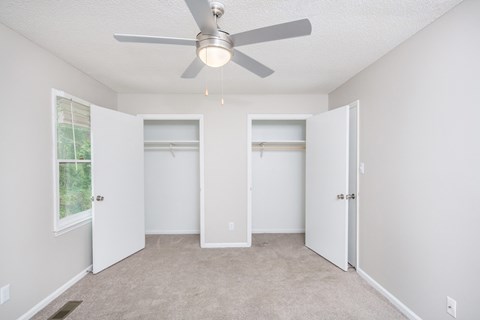 an empty room with a ceiling fan and two closets