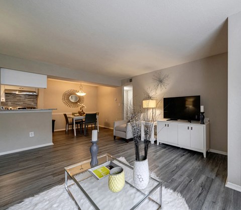 A modern living room with a glass coffee table and a flat screen TV.