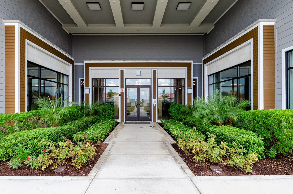 the entrance to a building with a sidewalk and plants at Lofts at South Lake, Clermont, 34711