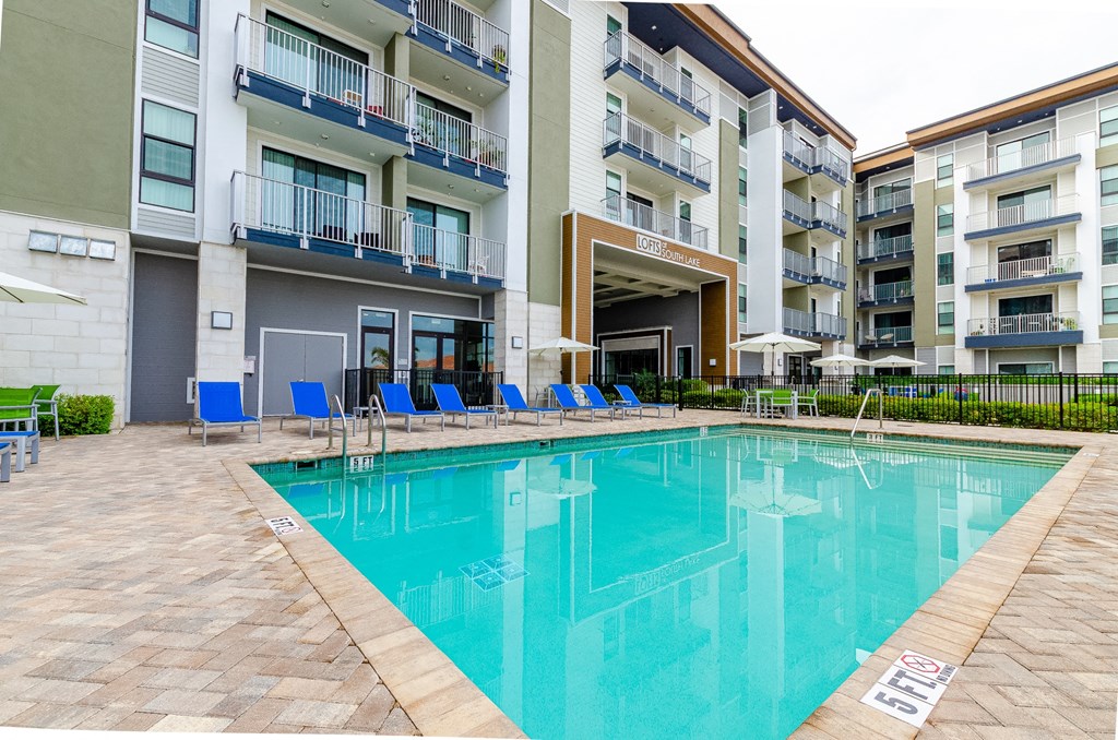 a swimming pool with blue chairs in front of an apartment building at Lofts at South Lake, Clermont, 34711