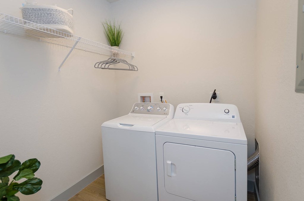 a white washer and dryer in a white room with a shelf above it at Lofts at South Lake, Clermont, FL, 34711