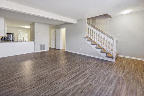 the living room and staircase of a renovated house with wood flooring