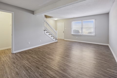 the living room and dining room of an empty home with wood flooring