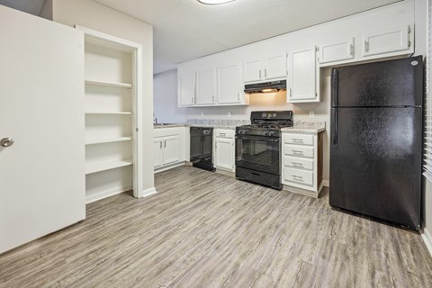 an empty kitchen with white cabinets and black appliances