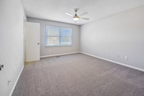 an empty living room with a ceiling fan and a window