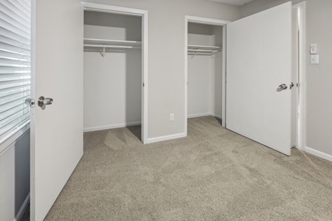an empty bedroom with two closets and a carpeted floor