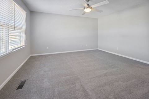 an empty living room with a ceiling fan and a window