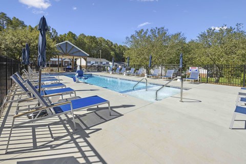 A pool area with sun loungers and a building in the background.