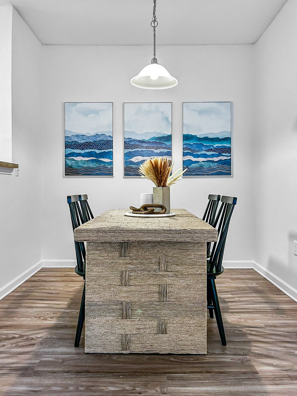 A wooden table with a vase of dried flowers on it.