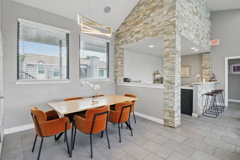 A dining room with a stone fireplace and a table with chairs.