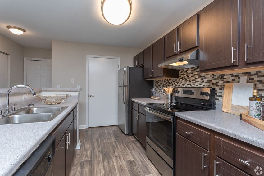 a kitchen with dark wood cabinets and faux granite countertops