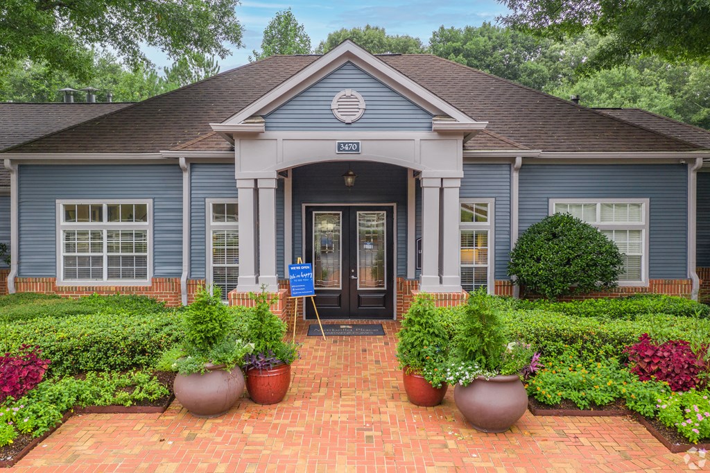 a blue building with a brick walkway and potted plants in front of it